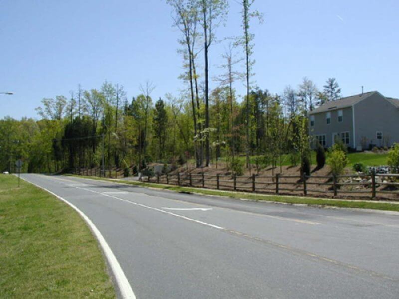 Three rail estate fencing, split rail fencing, mulch and greenery for residential neighborhood at entrance of subdivision